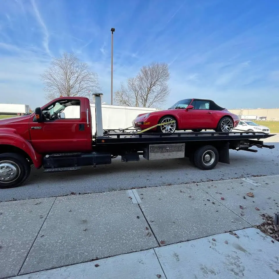 Red flatbed with a red sports car loaded on the bed