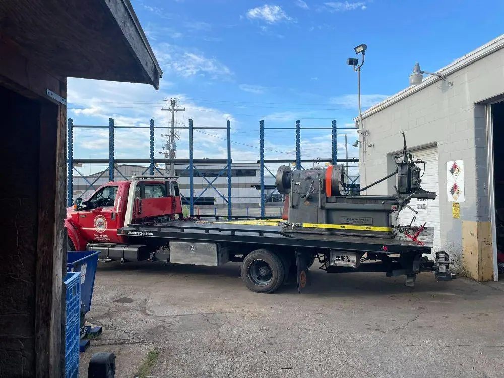Flatbed parked in a yard bay beside a shop